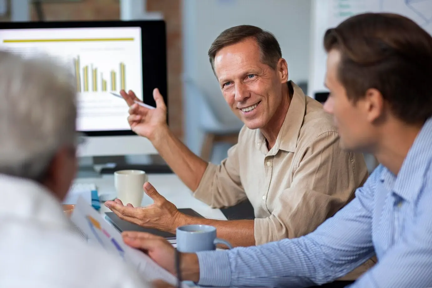 Personen nutzen ein digitales Gerät während eines Meetings.