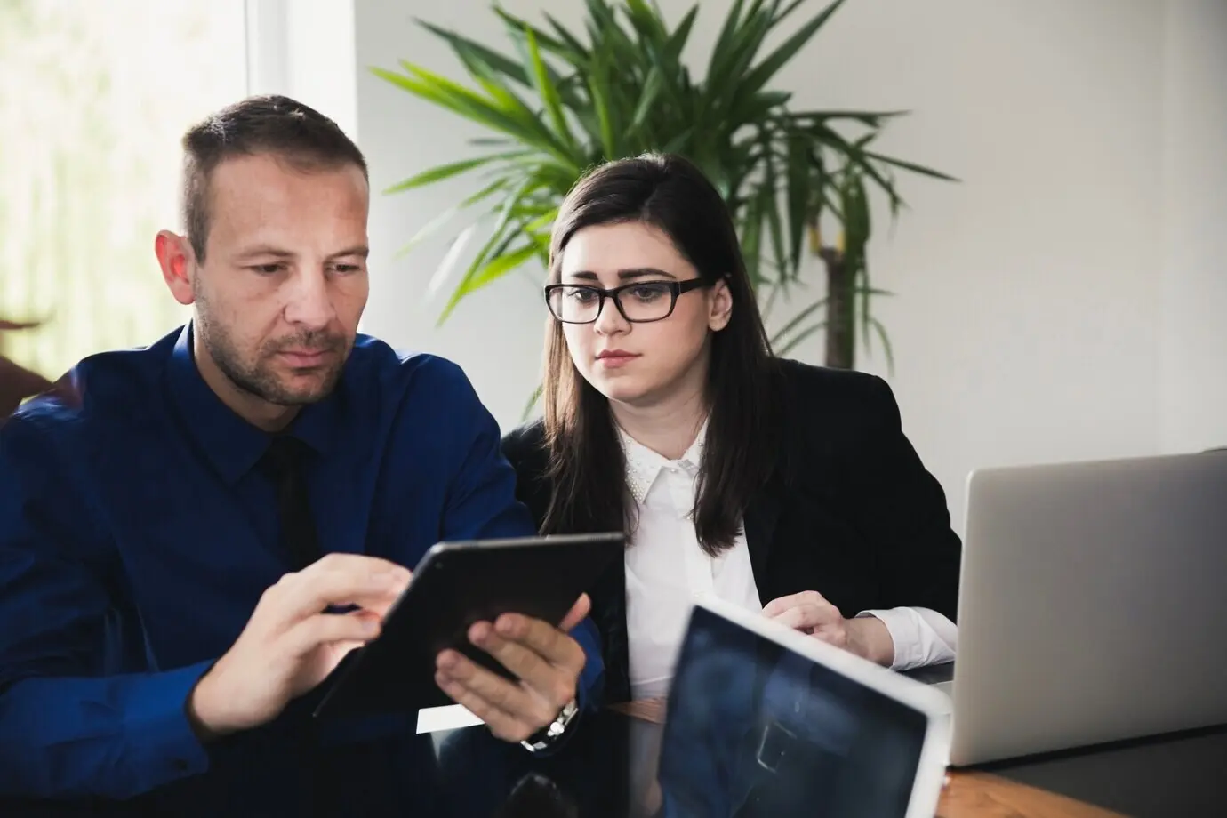 Zwei Personen im Büro betrachten ein Tablet.